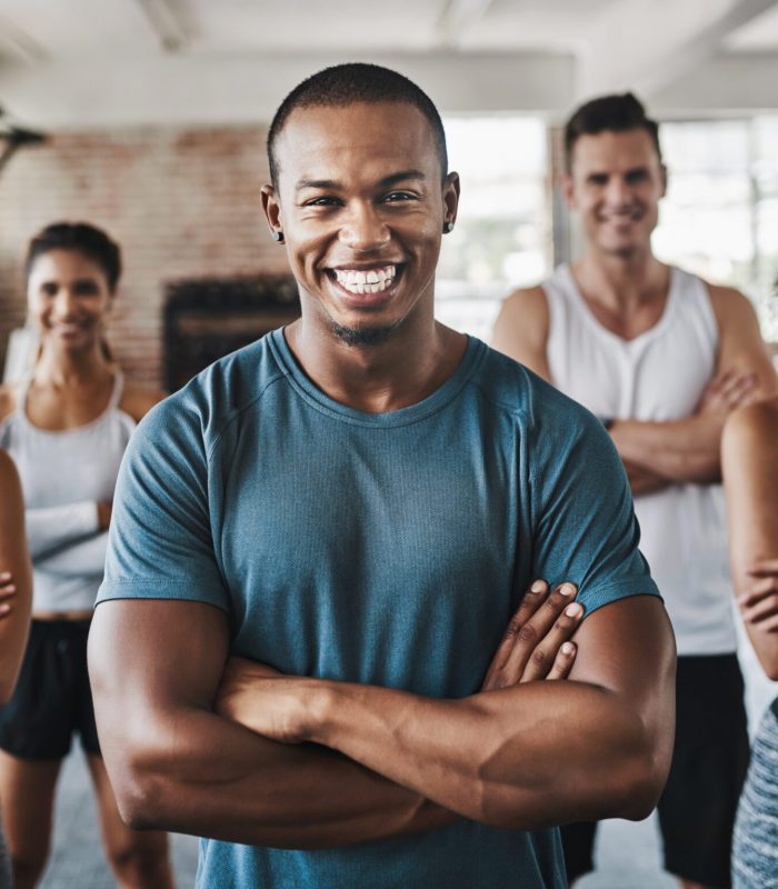 Portrait of a group of confident young people working out together in a gym.
